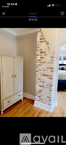 A white cabinet is in a room with a stone pillar.