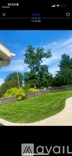 A photo of a house with a green lawn and a tree in the background.