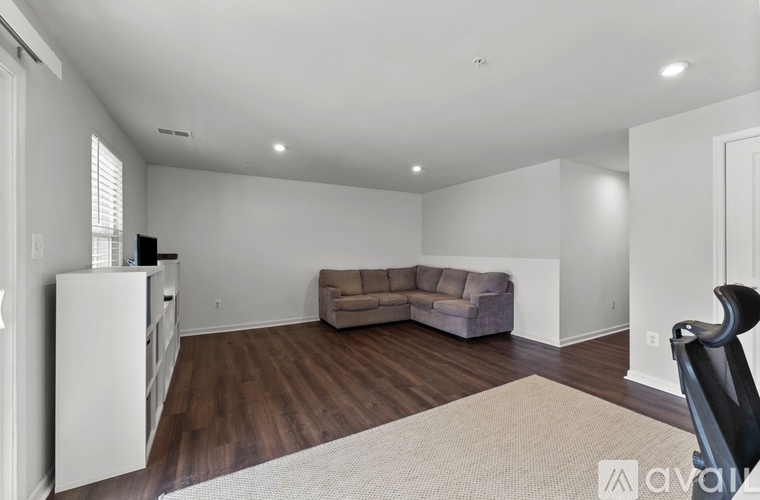 A living room with a grey couch and a white refrigerator.