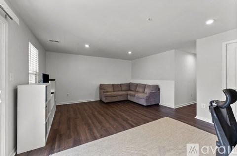A living room with a grey couch and a white refrigerator.