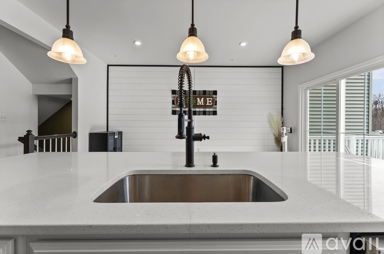 A modern kitchen with a stainless steel sink and pendant lights.