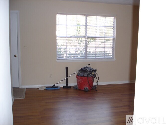 A room with a red vacuum cleaner and a blue mop on the floor.