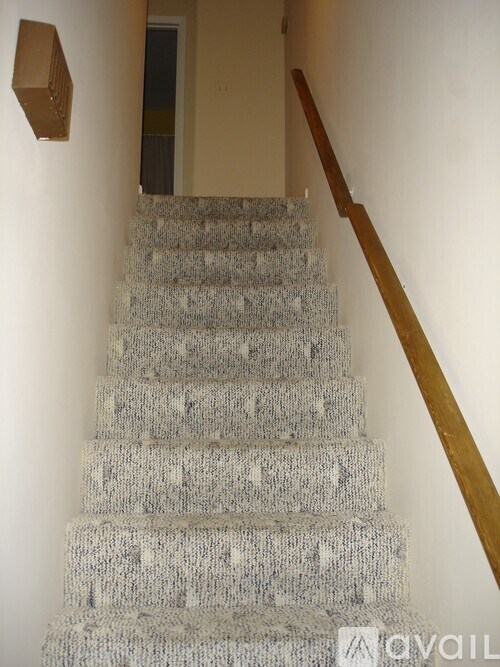A staircase with a wooden handrail and a cardboard box on the wall.