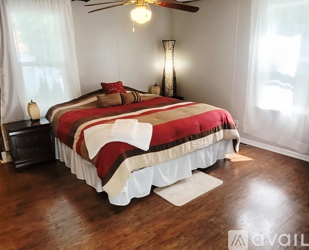 A bedroom with a bed covered in a red and white comforter.