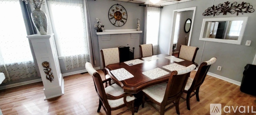 A dining room with a wooden table surrounded by chairs.