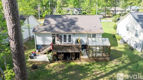A house with a deck and a tree in front.