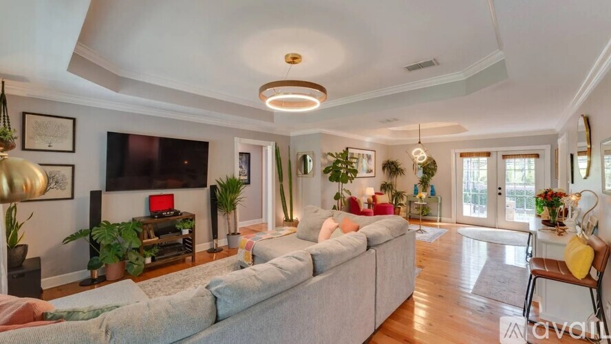 A living room with a grey sofa and a television on the wall.