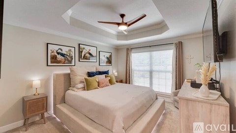A bedroom with a bed, a ceiling fan, and a nightstand with a lamp.