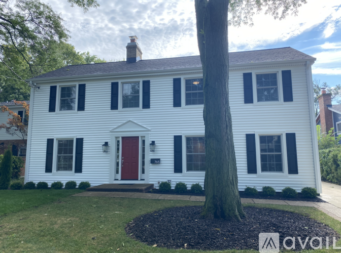 A white house with a red door and black shutters.