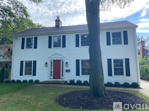 A white house with a red door and black shutters.