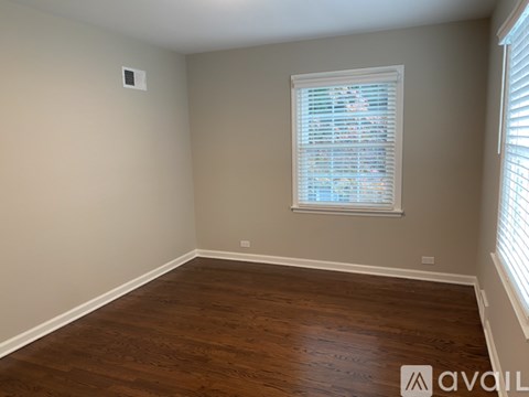 A room with wooden flooring and a window with blinds.