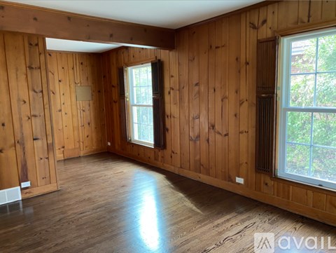 A room with wooden walls and a window on the right side.