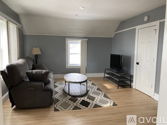 A living room with a grey couch, a round table, and a television.
