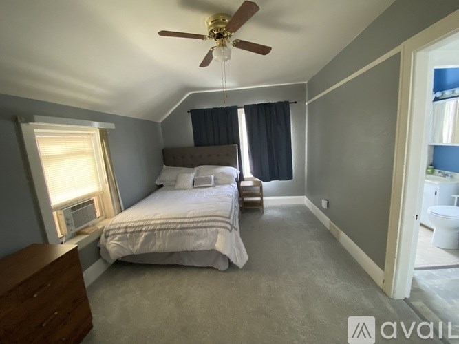 A bedroom with a bed, dresser, and window.