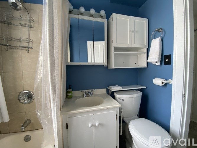 A bathroom with blue walls and white fixtures.