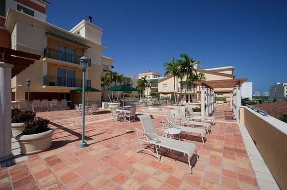 a patio with white chairs and tables and buildings
