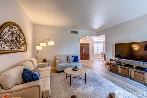 A living room with a couch, chairs, and a television.