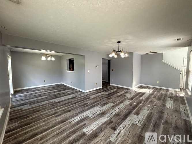 A spacious room with wooden flooring and a chandelier.