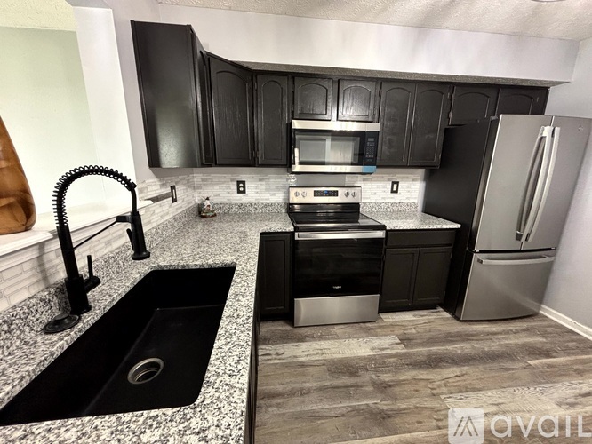 A kitchen with black cabinets and a granite countertop.