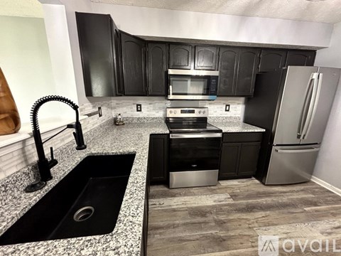 A kitchen with black cabinets and a granite countertop.