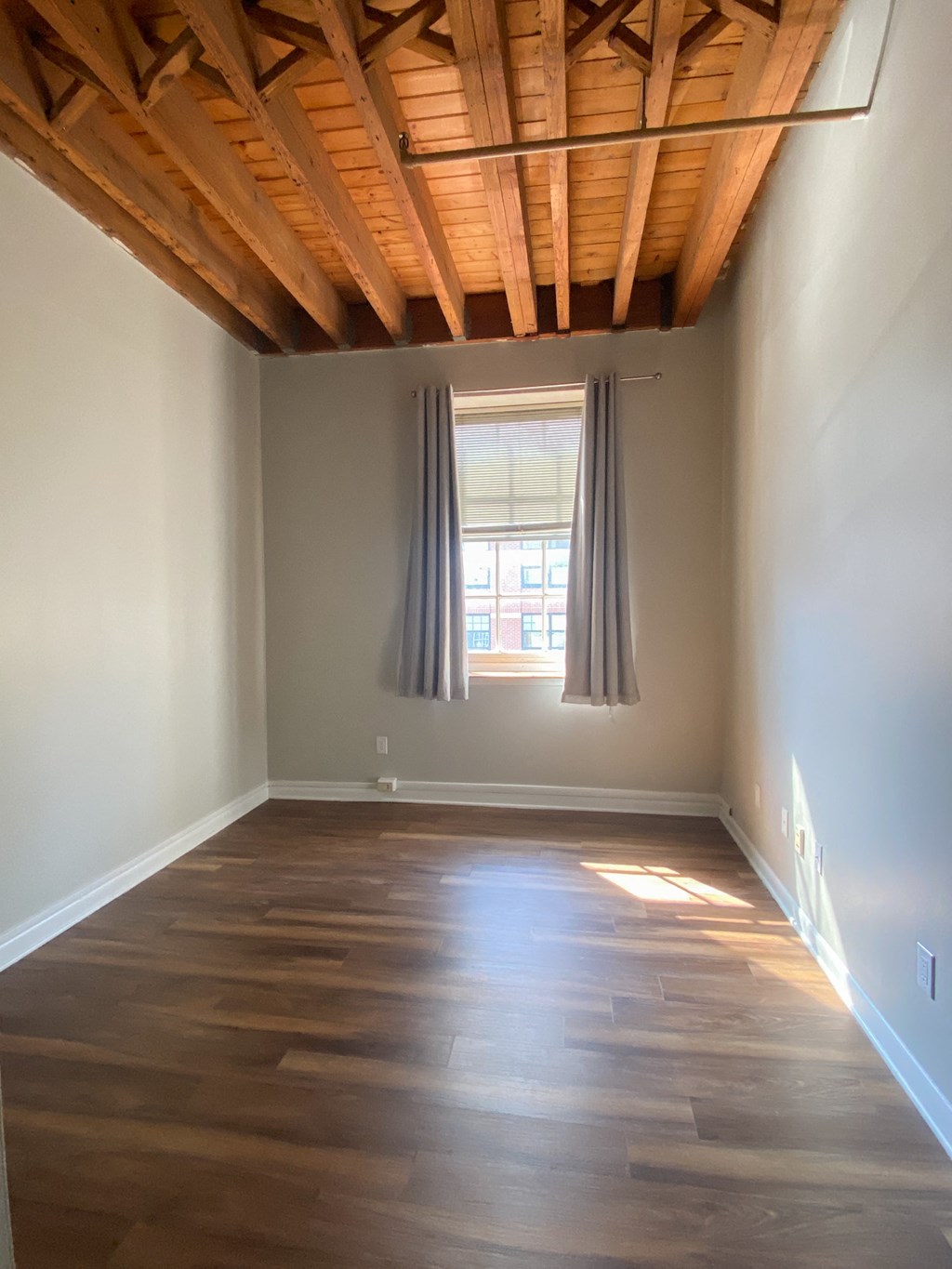 an empty room with wooden floors and a window