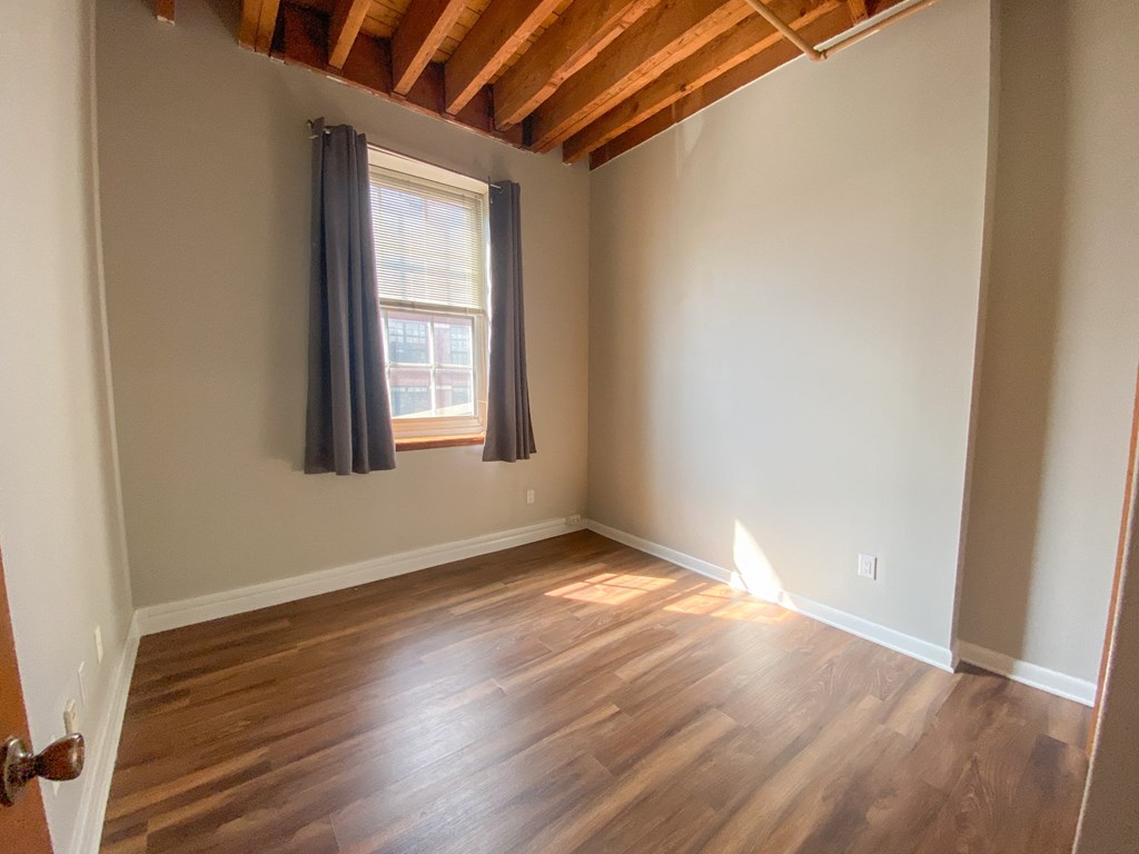 an empty room with wood floors and a window
