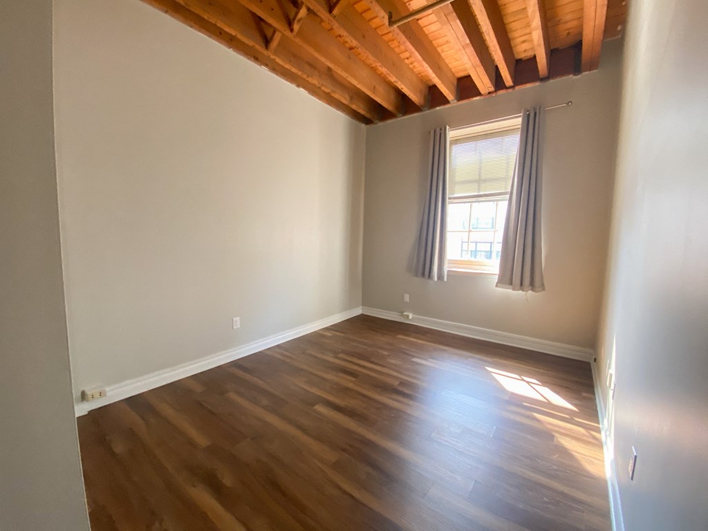 an empty room with wooden floors and a window