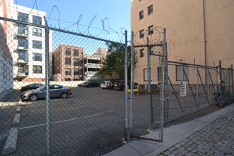 a city parking lot with a chain link fence and cars in front of a building
