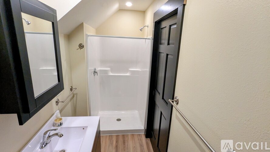 A bathroom with a sink, mirror, and shower.
