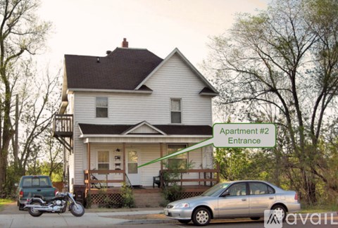 A house with a car parked in front and a motorcycle parked in front of the house.