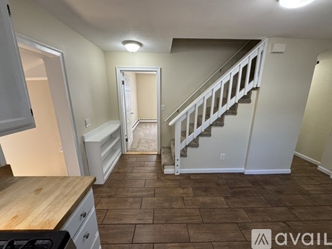 A kitchen with a wooden counter top and a staircase in the background.