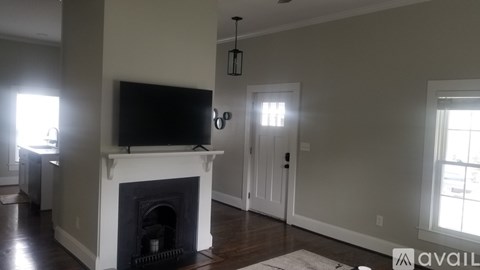 A living room with a fireplace and a television mounted above it.