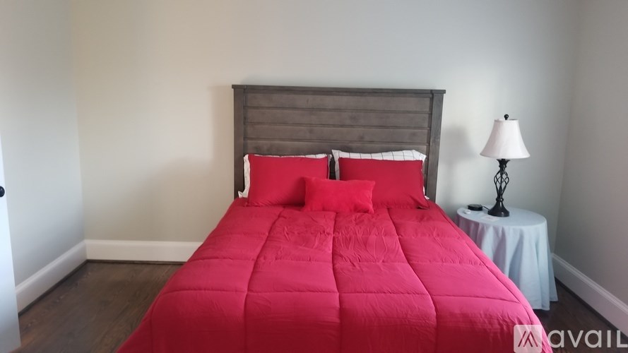 A bed with a red comforter and two red pillows sits in a room with a wooden headboard.