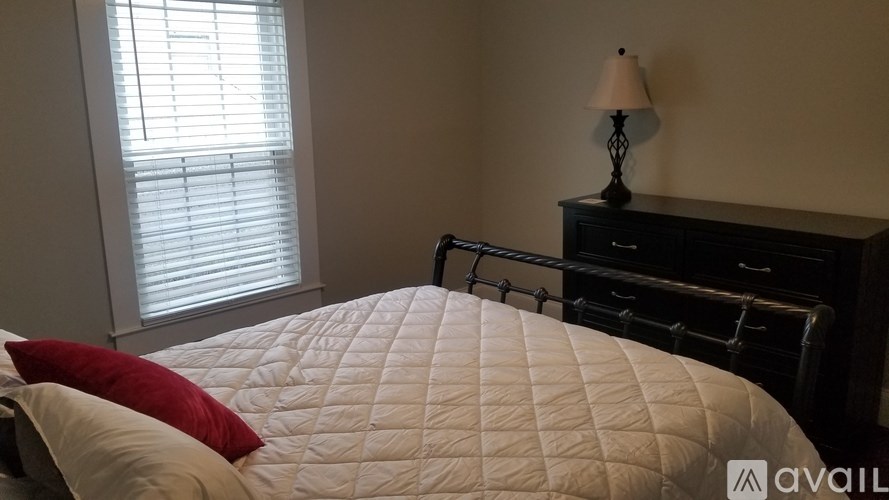 A bedroom with a bed, nightstand, and window with blinds.