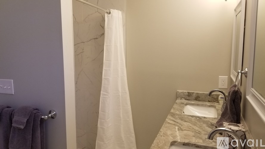 A bathroom with a marble counter top and a white shower curtain.