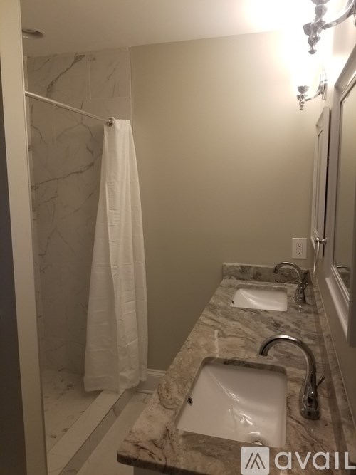 A bathroom with a marble counter top and a white shower curtain.