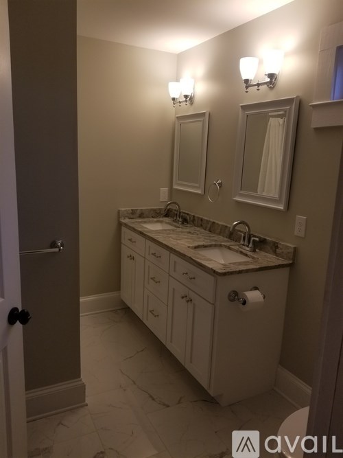 A bathroom with a sink, mirror, and light fixture.