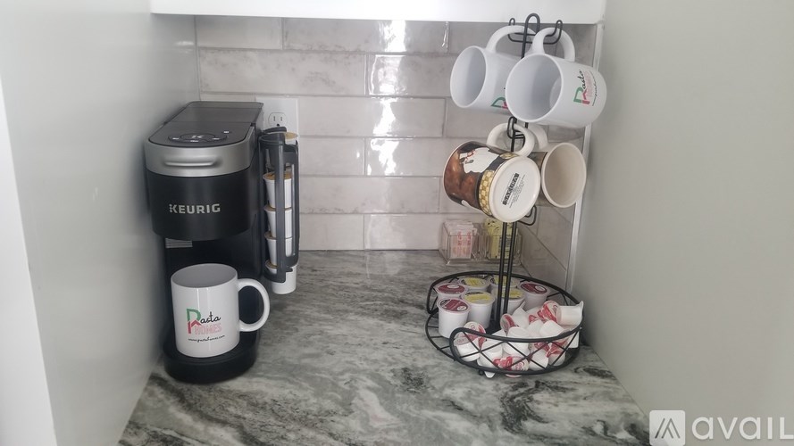 A Keurig coffee maker is on a marble countertop next to a cup with the word "Pure" on it.
