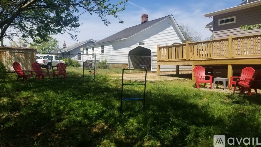 A backyard with a wooden deck and red chairs.
