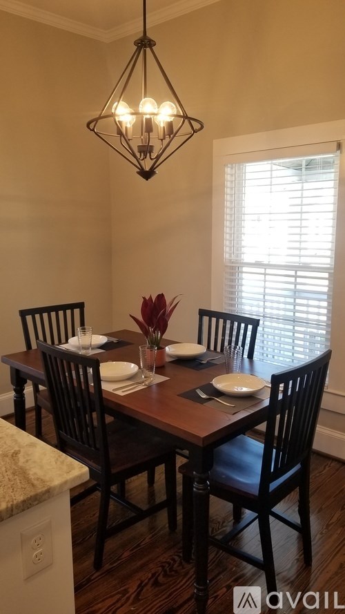 A dining room with a table set for two and a chandelier hanging from the ceiling.