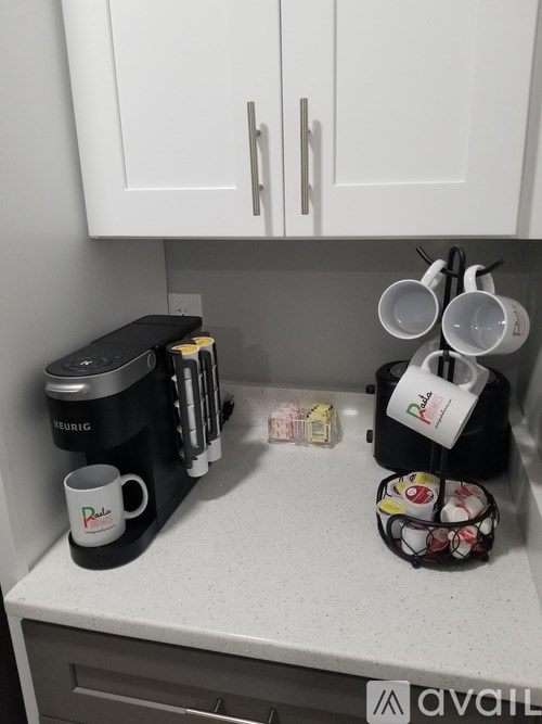A kitchen counter with a coffee maker, a mug, and a cup holder.