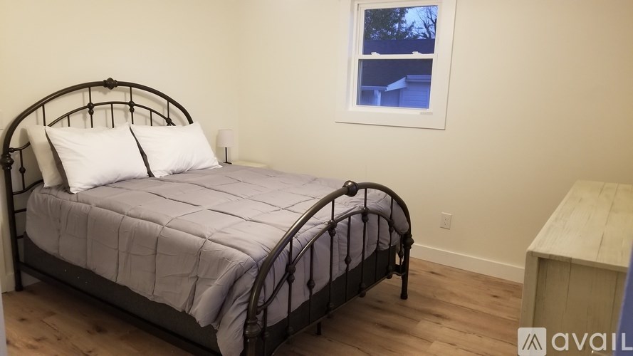 A bed with a white pillow and a grey comforter is in the image.