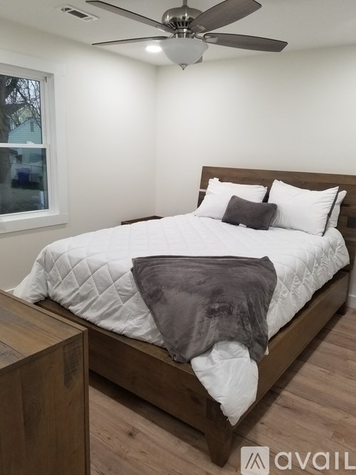 A bedroom with a bed, pillows, a ceiling fan, and a window.