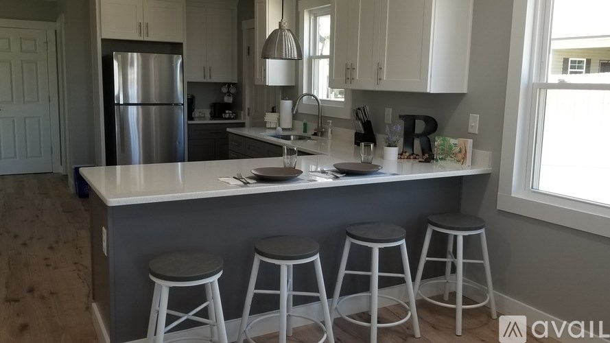 A kitchen with white cabinets and a large island with four stools.