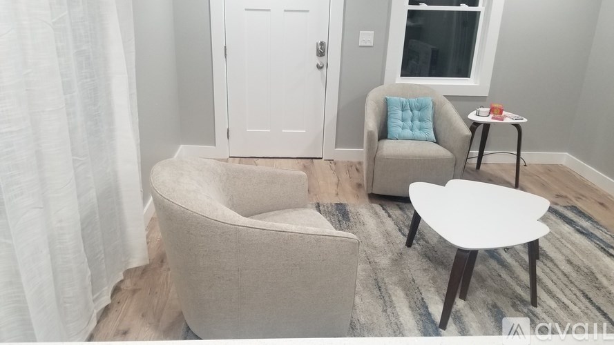 A living room with a grey couch, a white table, and a blue pillow.