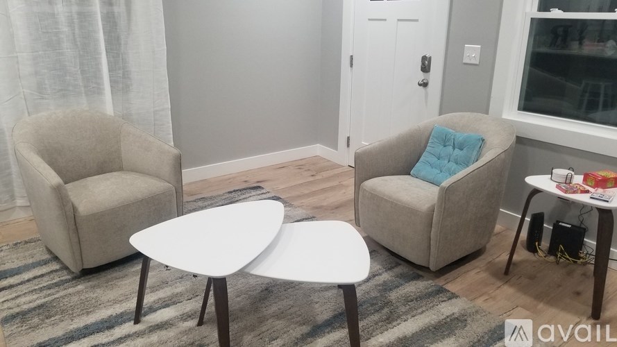 A living room with two chairs, a table, and a rug.