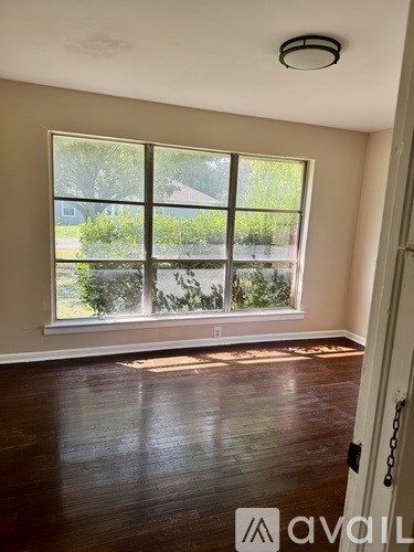 A room with wooden floors and a large window overlooking a garden.