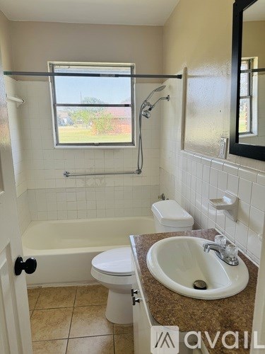 A bathroom with a tub, toilet, sink, and mirror.