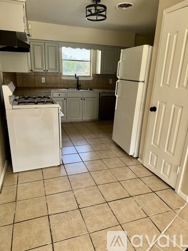 A kitchen with a white fridge and a white door.