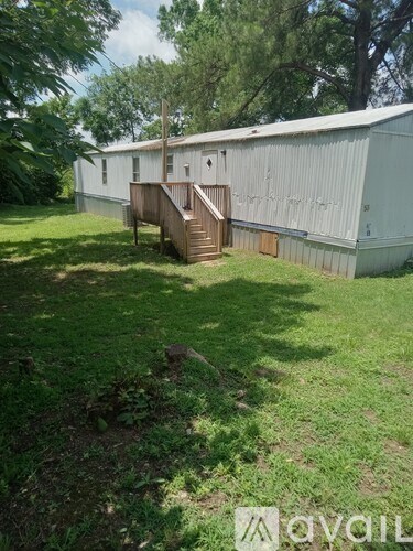 A white building with a wooden staircase leading to a door.